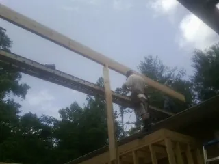 Carpenter setting a ridge beam over a new addition frame — Ice Dam Removal by Roofing Brothers in Deer Creek