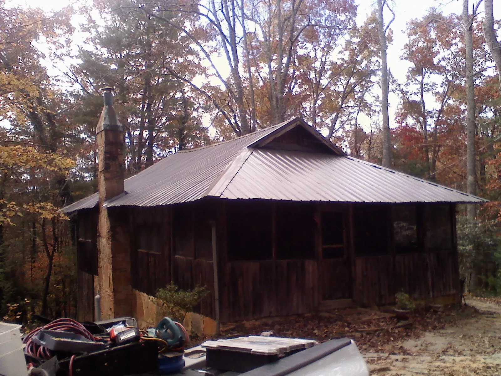 Brown metal hip roof on an old cabin with a stone chimney in Deer Creek
