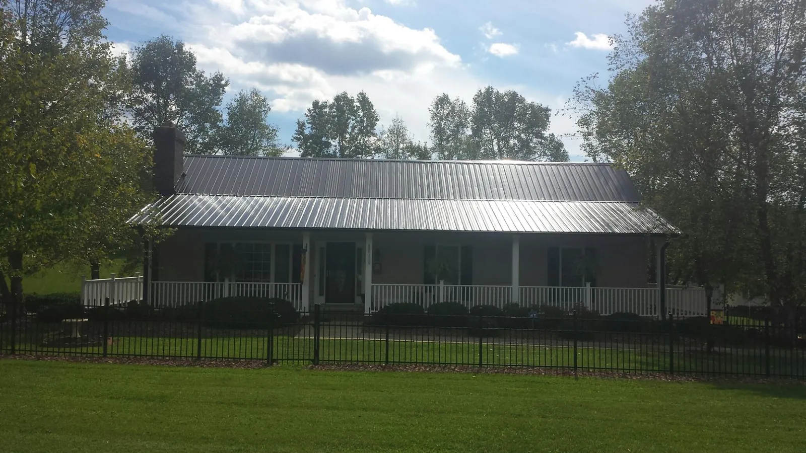 Gray metal roof on a brick ranch with a full width front porch — Gutter Guard Installation work by our crew in Deer Creek