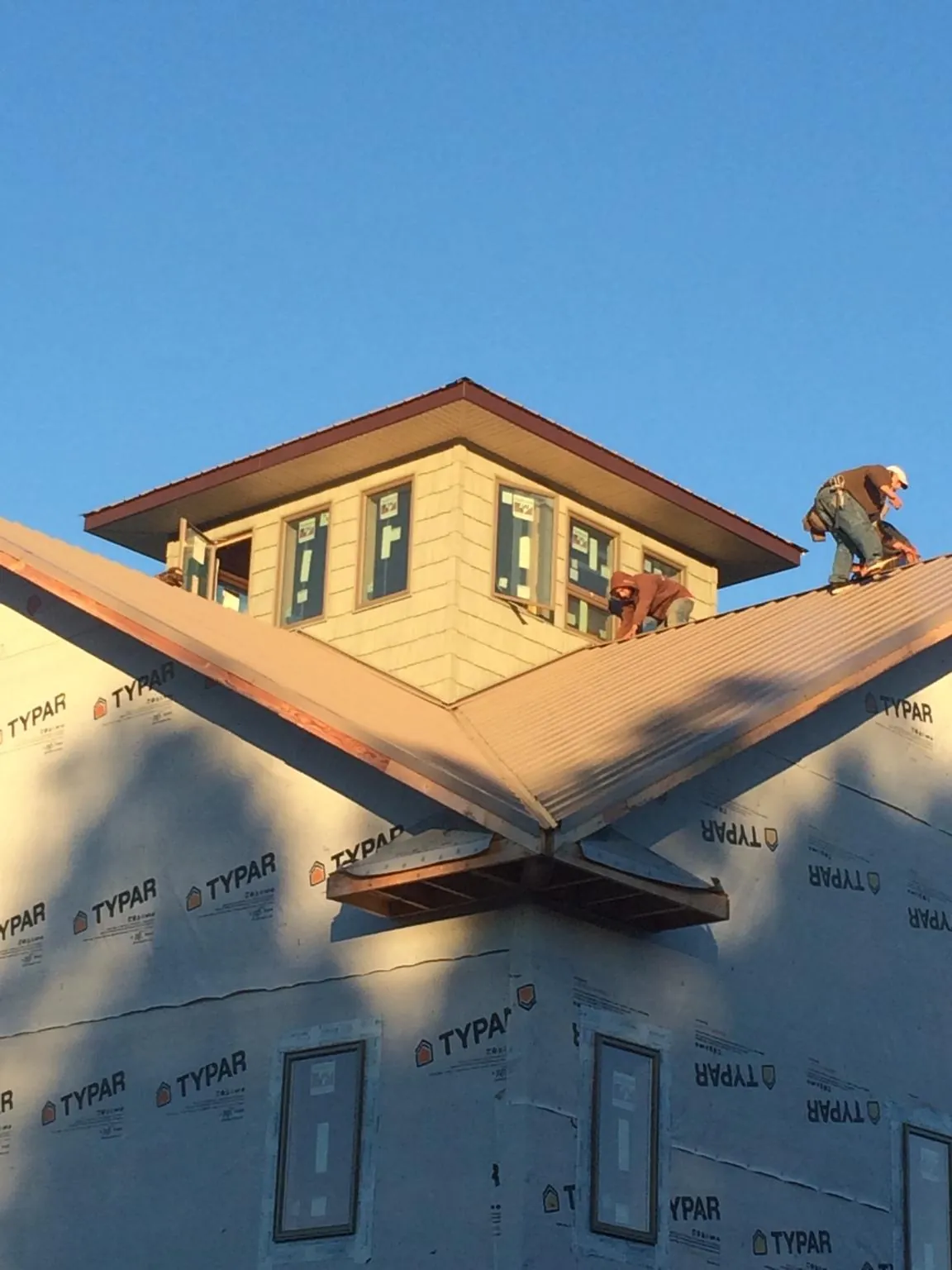 Roofers working around a rooftop cupola on a new metal roof at sunset — Roof Waterproofing in Deer Creek by Roofing Brothers